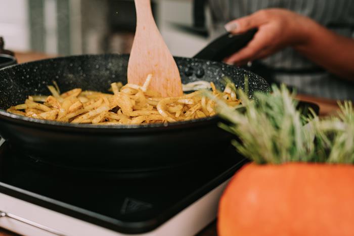 Come si fa la vellutata di zucca، padella con mestolo di legno، soffriggere la cipolla