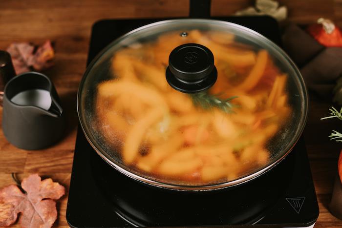 Come si fa la vellutata di zucca و padella con coperchio و padella su un fornello elettrico و fette di zucca