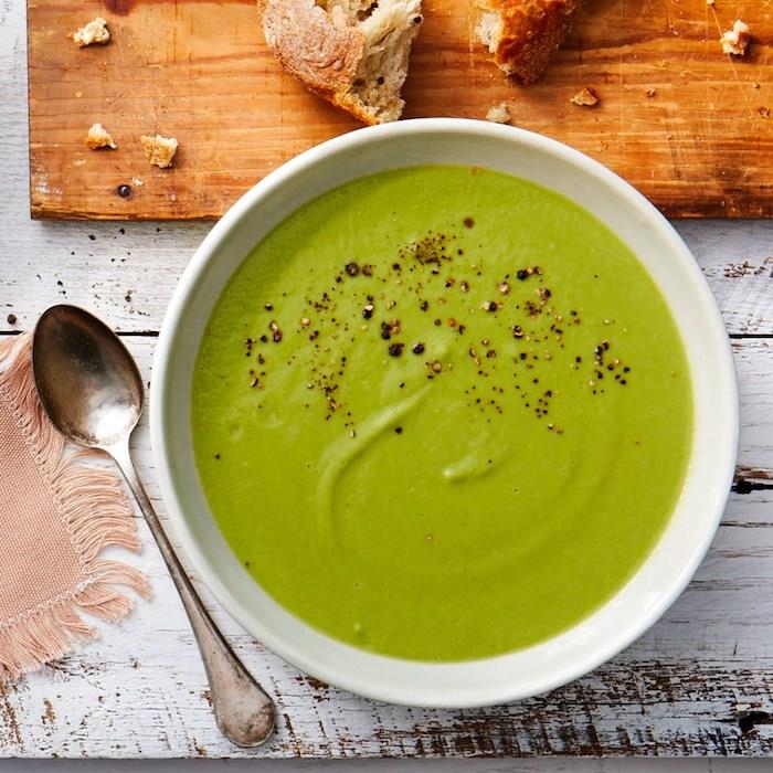 Zuppe dietetiche ، piatto con vellutata verde ، tagliere di legno con pezzi di pane