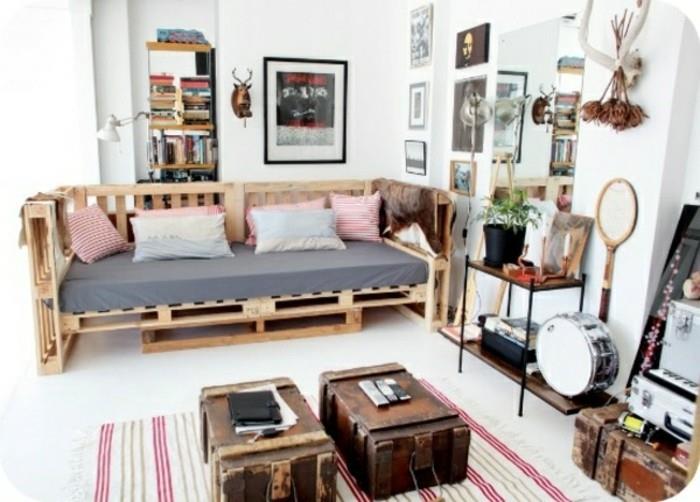 Ambiente arredato con divano in a palette, valigie vintage utilizzate come tavolini