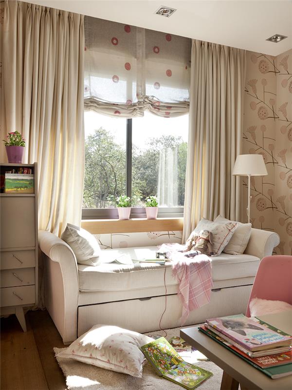 läshörna framför fönstret, vit läderbänk med dekorativa kuddar, pastellrosa stol och beige skrivbord