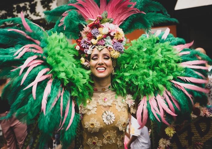 Blommig klänning i gyllene nyans, överdådiga fjädrar på axlarna, carnava -kostym för kvinnor, de vackraste kläderna