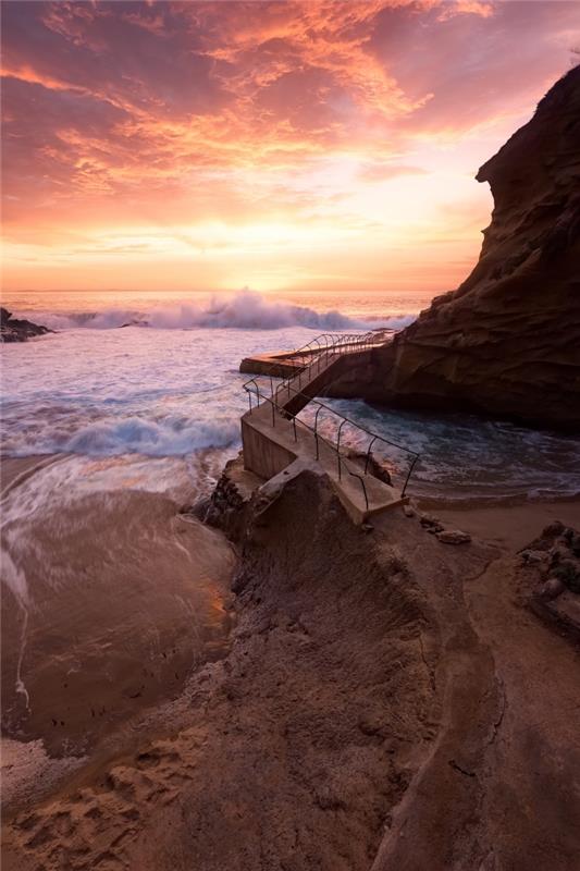 vyberte tapetu prírodnú tapetu, fotografiu oceánu, ktorého vlny pri východe slnka narážajú do skál