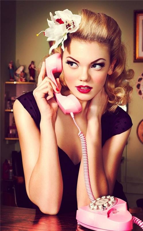 blondínka s retro rockabilly účesom z 50. rokov, zadným banánom a pin up makeupom s ružovým telefónom