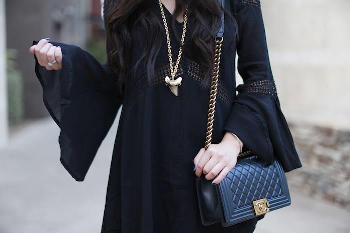 kvinna häxa kostym look idé, svart klänning med långa utsvängda ärmar, svart handväska, guld häxhalsband