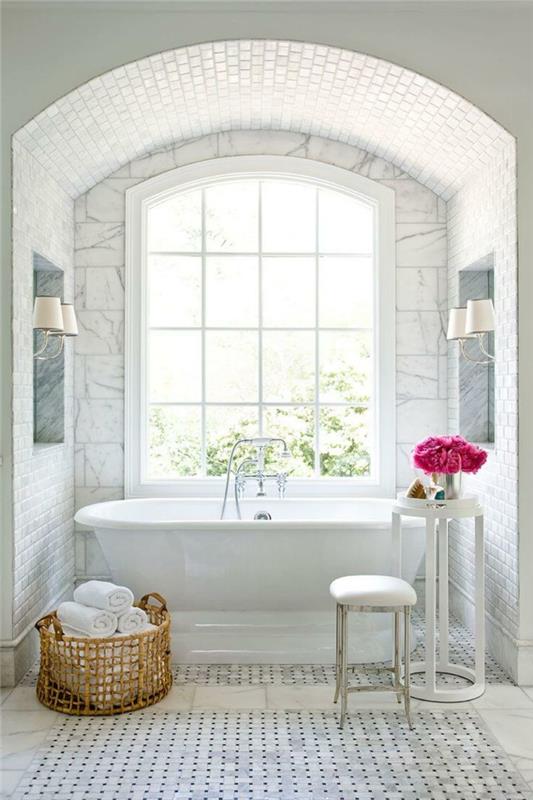 vitt badrum, vävd korg, liten pall, högt bord, bukett med rosa blommor, välvd altandörr, vintage kakel