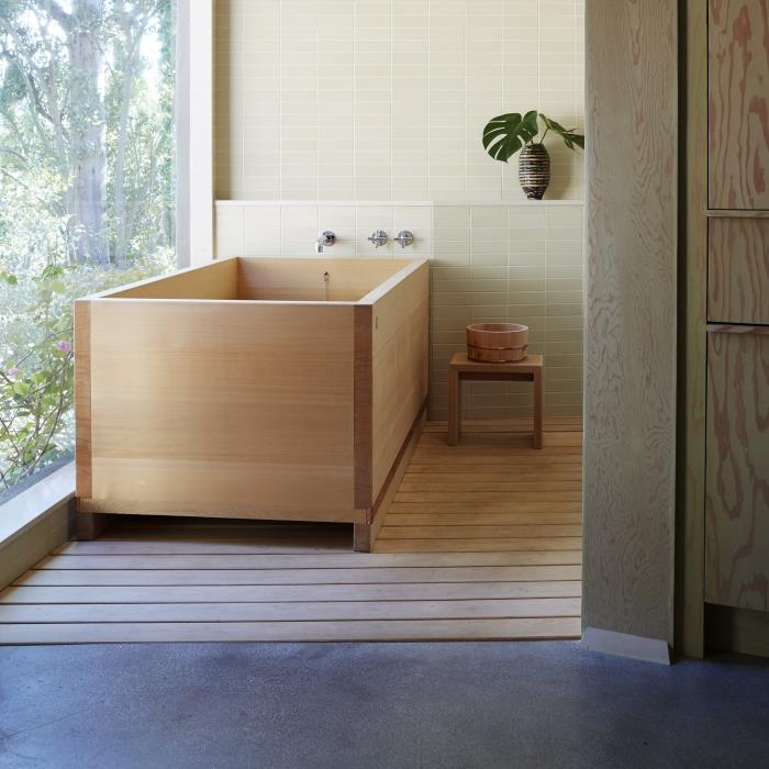 Japonský model drevenej vane inštalovaný na koberci zo svetlého dreva, kúpeľňová dekorácia v Zenovom štýle s rastlinami a drevom