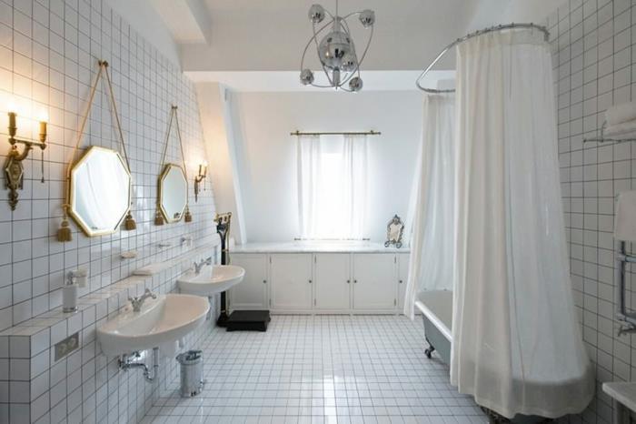 helvitt badrum, åttkantiga speglar med gyllene ram, vita plattor, retro vit handfat, gammalt badkar