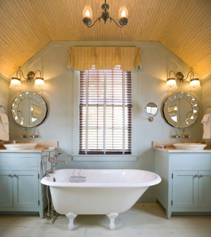 asymmetriskt badkar, runda art deco -speglar, två handfat och blå fåfänga, sluttande tak
