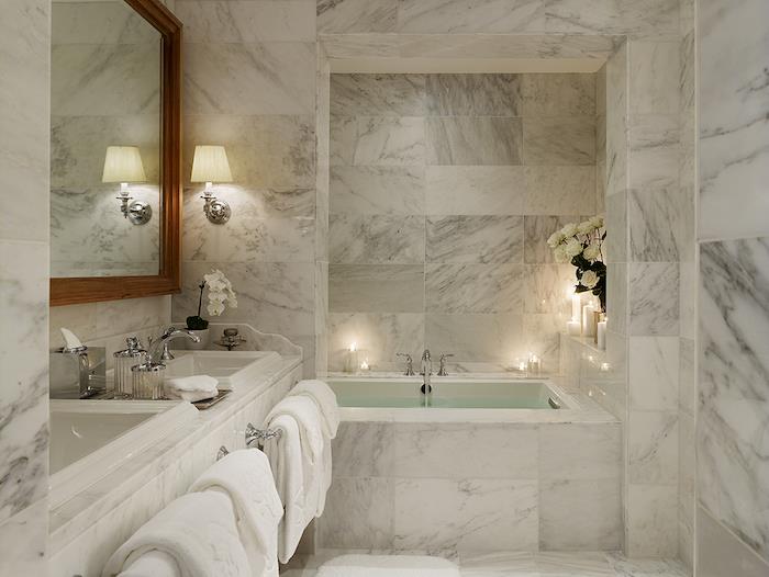 ديكور حمام ، مناشف بيضاء ، رصف رخامي ، إطار مرآة خشبي ، حوض استحمام ، شموع