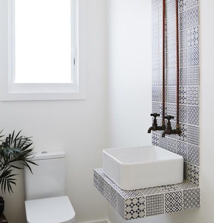 malá dizajnová kúpeľňa s bielym umývadlom a čiernobielymi pruhovanými dlaždicami, wc a bielymi stenami