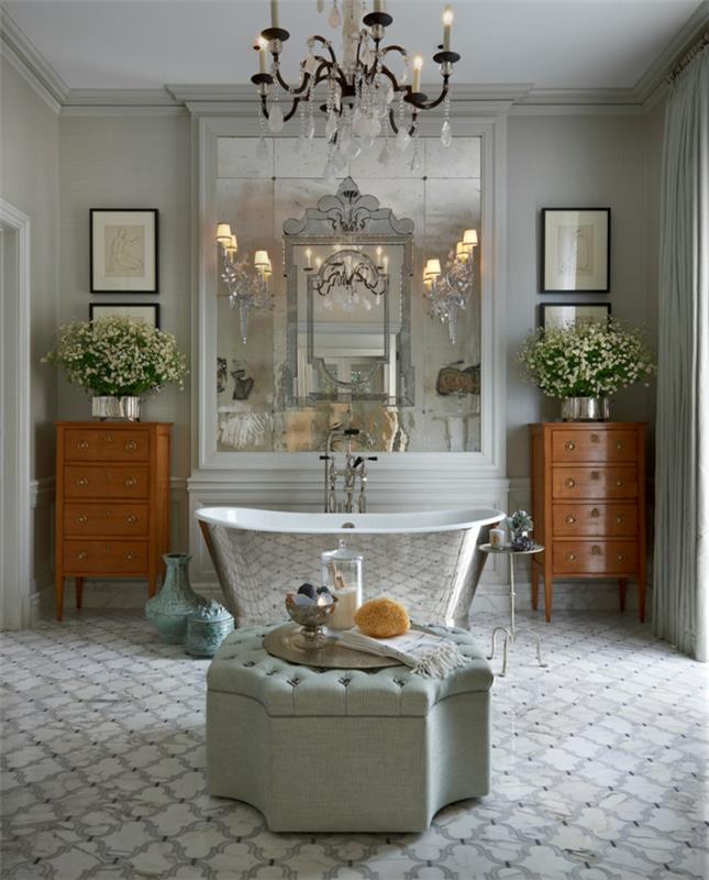 grå tuftad ottoman, silverfärgat badkar, eleganta vägglampor, lackerade trämöbler, stor rektangulär spegel