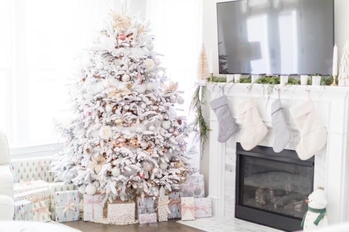 kokande dekoration i ett vitt vardagsrum till jul med ett stort julgran dekorerat i vitt och metalliskt
