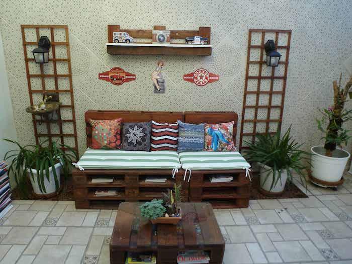 DIY paletová lavica s vankúšom zelenej a bielej farby, konferenčný stolík z paliet, sivobiela obkladaná stena, boho chic dekoratívne vankúše, kvetináče
