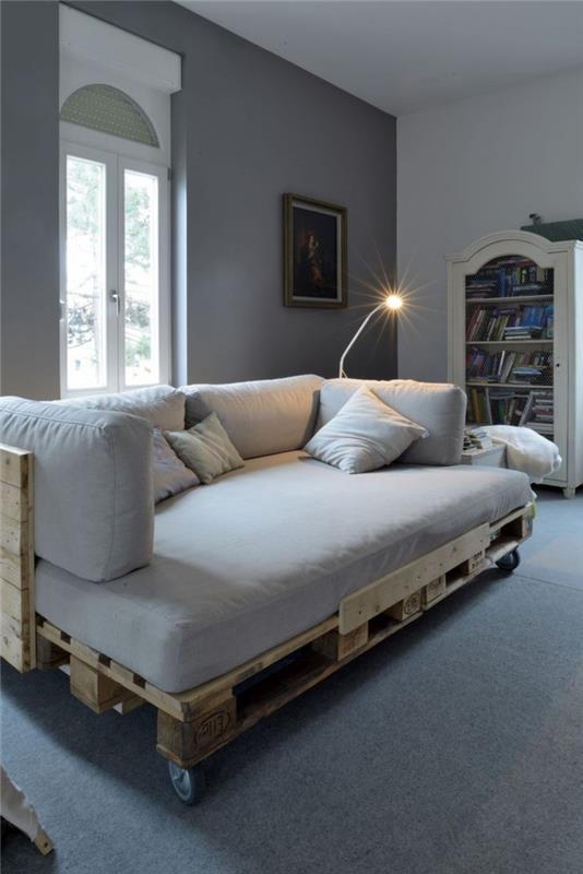 sivá obývacia izba s paletovou sedačkou na kolieskach vybavená matracom a zodpovedajúcimi vankúšmi