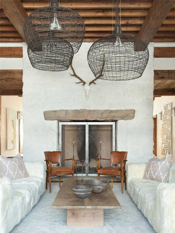 rustikt vardagsrum, ljusgrå matta, soffa, vit pälsfilt, soffbord i rått trä, stolar, hängande lampor i metall, hus i träram