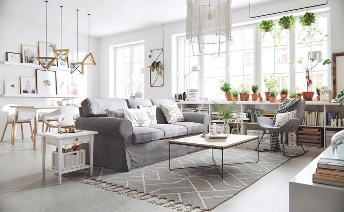 jedáleň otvorená do sivobielej obývačky so škandinávskym kobercom a sivou sedačkou, bielym jedálenským kútom, bielou odkladacou poličkou, minimalistickým konferenčným stolíkom z dreva a kovu, dekorom zelených rastlín