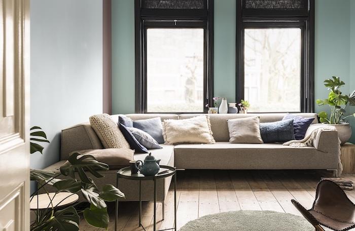 akvarelové deko, namodralý seladónový odtieň, svetlá deka, sivá sedačka, béžové, sivé a modré vankúše, čierny stolík, kožená stolička, zelené rastliny