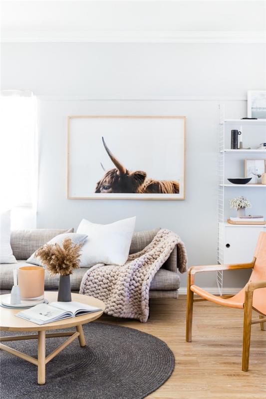 cocooning deco i ett vardagsrum i skandinavisk stil i neutrala toner, beige soffa med stor kuvert i rutnät, toppad med en fotoram i färger som harmoniserar med inredningen