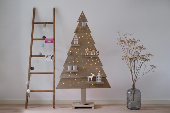 veľká sklenená váza, suché kvety, vianočný stromček osvetlený malými vianočnými lampami, vianočná dekorácia v škandinávskom štýle, rebrík so strapcovou girlandou
