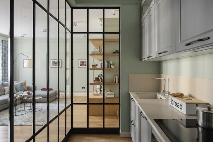 pekná kuchyňa, oddelenie obývačky s presklenou dielňou, obývačka v minimalistickom zariadení v sivom a drevenom prevedení