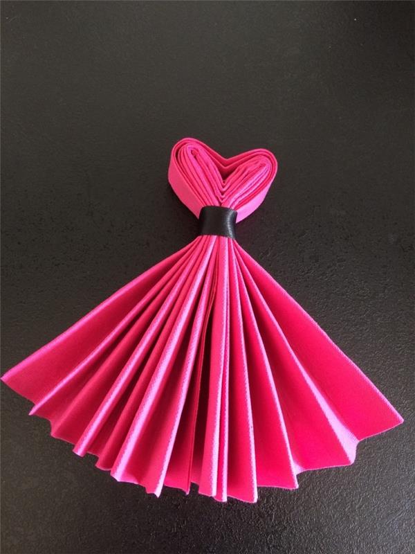 príklad, ako pomocou čiernej stužky zložiť fuchsiový ružový papierový obrúsok v tvare princeznovských šiat