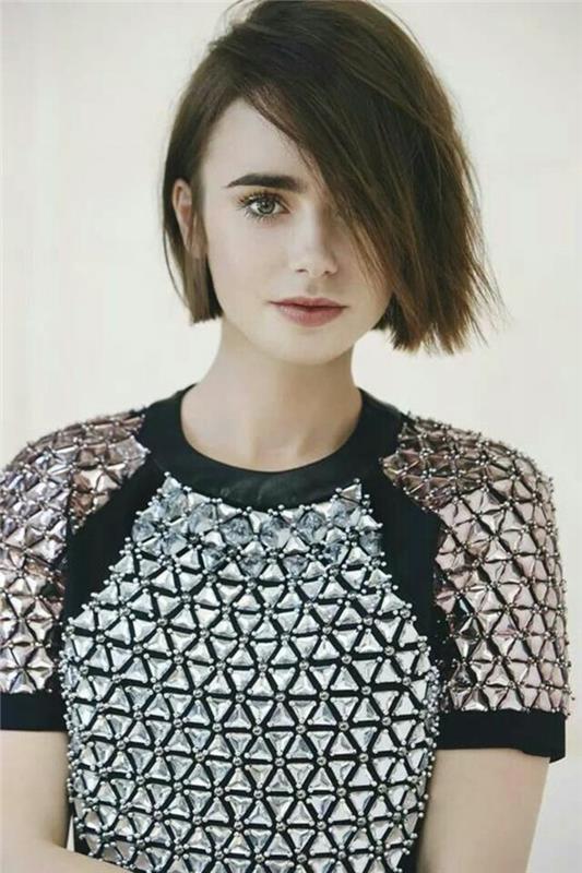 lily collins s krátkym, tmavohnedým bobom, ofinou zakrývajúcou jej oko, na sebe čierny top, s trojuholníkovými striebornými ozdobami