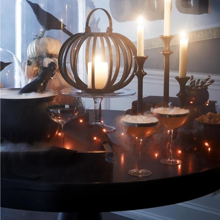 Halloween -förberedelser, bordsdekoration med glas champagne och ljus, modeller av vita pumpor