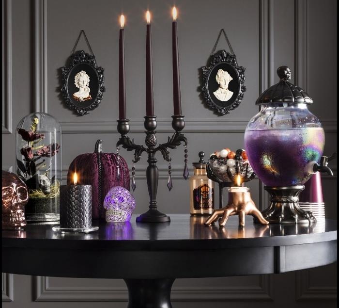DIY halloween deco, salox med grå väggar med porträtt i svart ram, svart runt bord med dekorativa Halloweenföremål