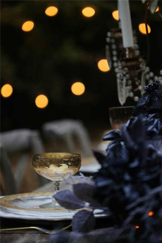 halloween bordsdekoration idé, ljus krans ovanför matbordet dekorerad med svarta torkade blad krans