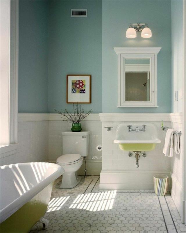 modrá stena, biele terakotové dlaždice, biela a zelená vaňa, skriňa so zrkadlom, umývadlo zo živice v bielej a zelenej farbe, rám na maľovanie