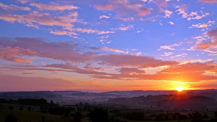 landskap av en lila himmel, orange sol ovanför en slätt, en liten by i Toscana, olivlundar, fredlig kvällsstämning