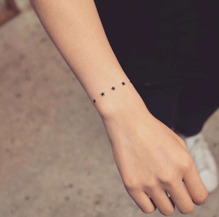 Mano tatuata con stelle, tatuaggio piccolo, donna con maglietta nera