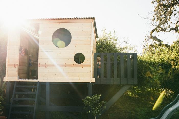 idé hur man bygger en stuga med en matt svartmålad terrass, modell av ett trähus med ett runt fönster