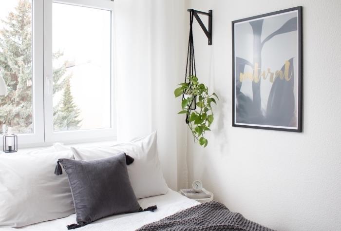 Skandinavisk sovrumsinredning med vita väggar med grå accenter och en hängande lampa med svart sladd