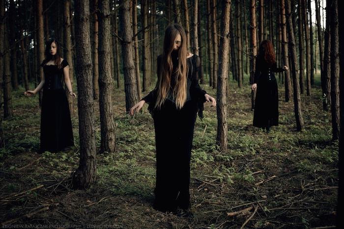 häxa coven klädd i långa svarta klänningar, häxlook utan smink, häxor i skogen, naturlig miljö