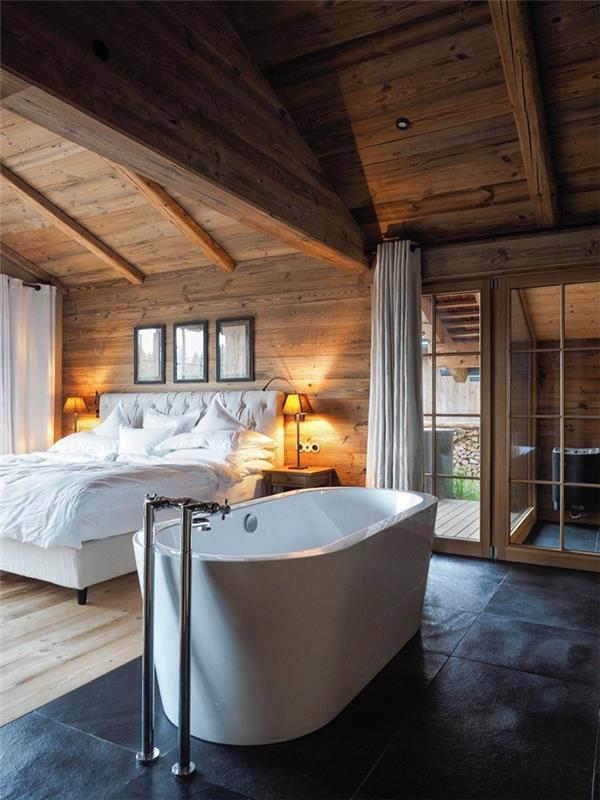 hlavná spálňová suita kúpeľňa chata dekor rustikálny strop spálne pokrývajúci odhalené drevené trámy voľne stojaca biela vaňa