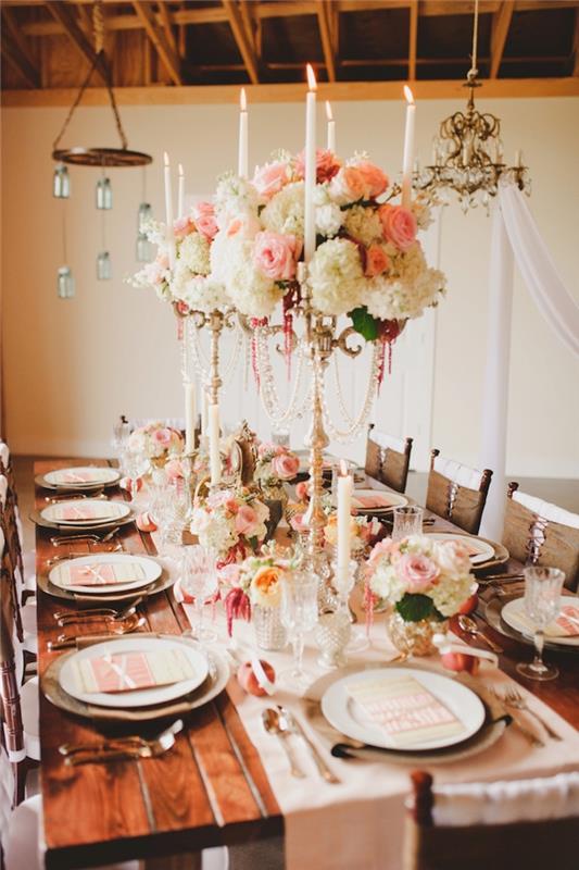 svietniky zdobené ružovými a bielymi kvetmi na výšku ako stredobod na bielom behúni na hnedom drevenom stole, drevené stropné dekorácie