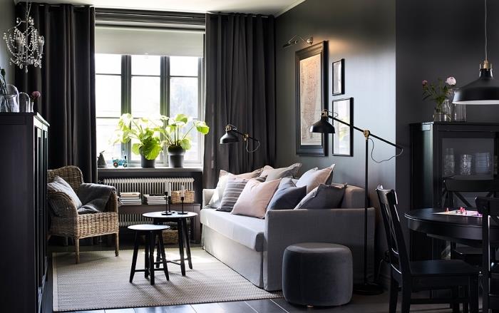 vardagsrumsdesign med mörka väggar med ljusgrå soffa täckt med dynor i pastellfärger och svartmålade trämöbler