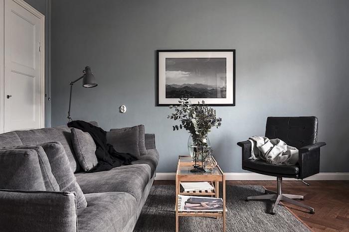 välkomnande atmosfär i ett vardagsrum med grå väggar med trä- och glasbord, grå soffmodell med kuddar