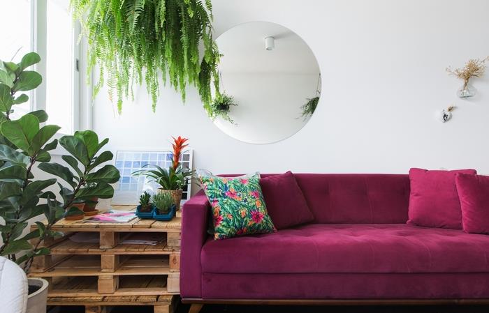 obývacia izba so zelenými akcentmi plná sviežosti kontrastujúca s paletovým stolom a zamatovou pohovkou s