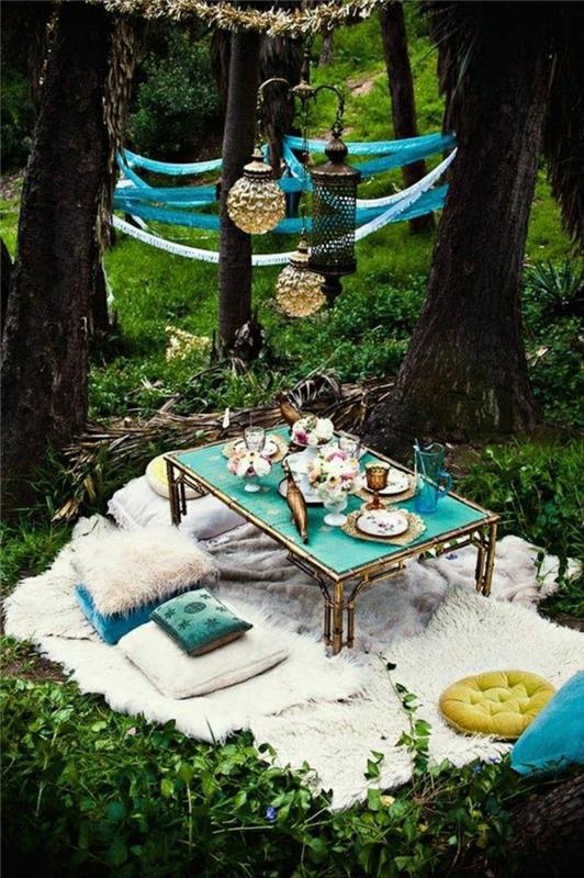 trädgård-picknick-gräsmatta-gröna-kuddar-beige-matta-dekoration-smidesjärn-bord