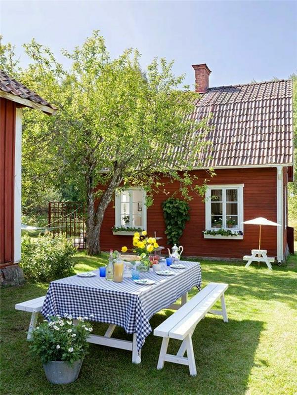 trä-bord-vit-bänk-duk-vit-blå-blommor-på-den-gröna-gräsmattan-bord