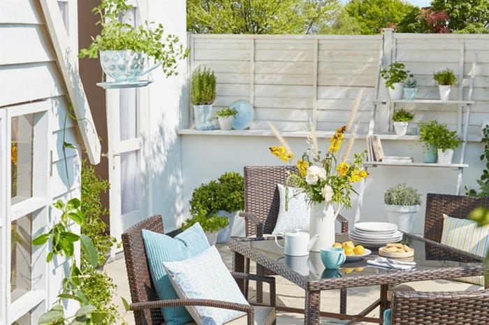 طاولة وكراسي حديقة مزخرفة مع وسائد زرقاء وأواني مزهرية وأواني زهور ، أفكار لشرفات خارجية ، تصميم حديقة صغير حديث