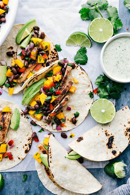 Ripieno tortillas, ciotola con salsa al coriandolo, fettine di avvocado, tacos con filetti di pollo