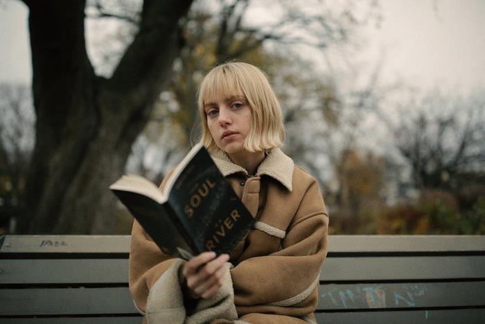 Idea per dei tagli capelli medi di Colore biondo con frangia، ragazza con libro in mano seduta su una panchina