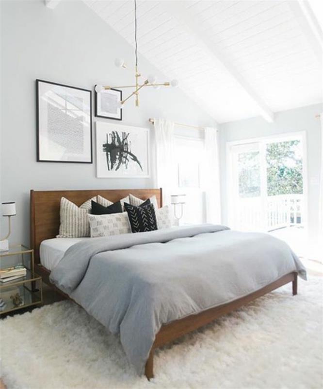 vit matta, träsäng, grått sängklädsel, kuddar i vitt, grått och svart, vit väggfärg, designerhängande ljus, dekorativa målningar