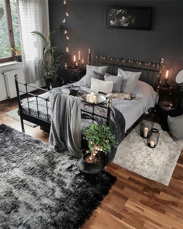 Železná posteľ, sivá stena a biely stôl, ľan a sivý koberec, ktoré kombinujú všetky dekorácie, svetlé girlandy