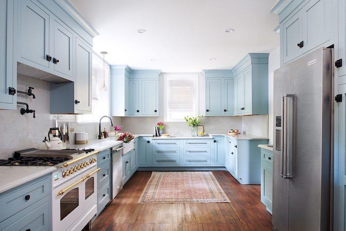 Biely kuchár, svetlo modré kabíny, orientálny koberec v kuchynskom trende 2020, kombinujú farby v kuchyni