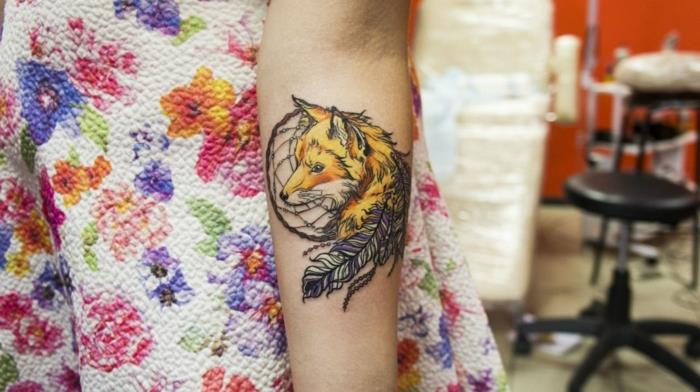 Dreamcatcher tatuering underarm, svart drömfångare, gula och lila fjädrar och orange gul rävdesign